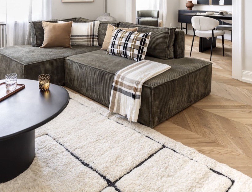 Salon avec canapé en velours olive, plaid à rayures et tapis berbère fait main