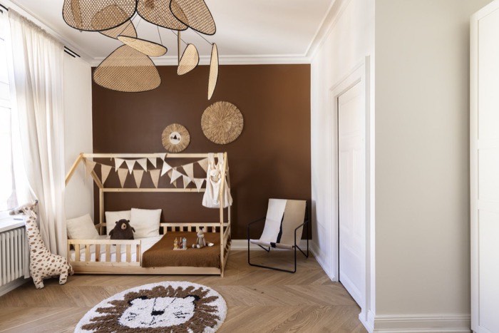 Chambre d'enfant avec mur terracotta, lit cabane en bois et suspensions en rotin