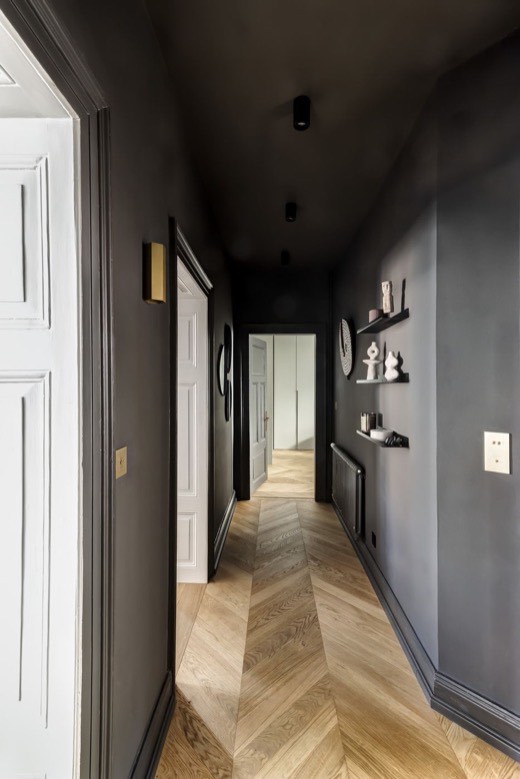 Couloir peint en noir mat avec parquet en point de Hongrie et étagères murales