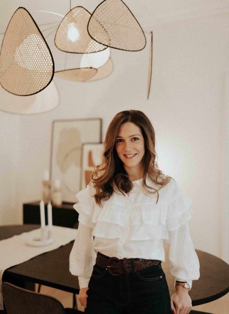 Emelyne Oster dans un intérieur qu'elle a décoré, sous des suspensions en rotin