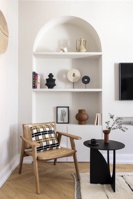 Niche en arche avec objets en céramique, fauteuil en bois et guéridon noir