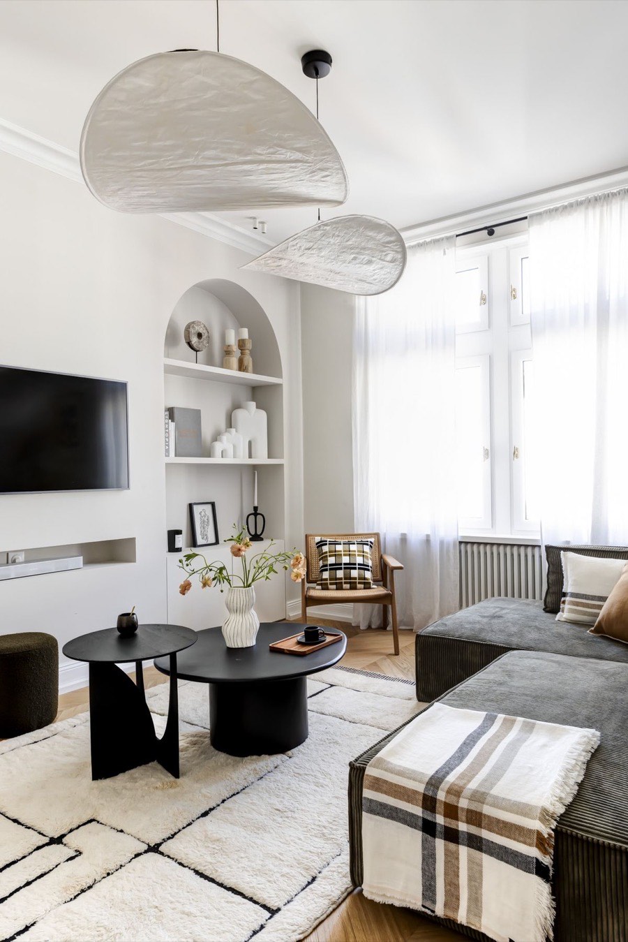 Séjour d'un appartement ancien rénové : niches en arche, suspensions en papier, canapé olive et tapis berbère
